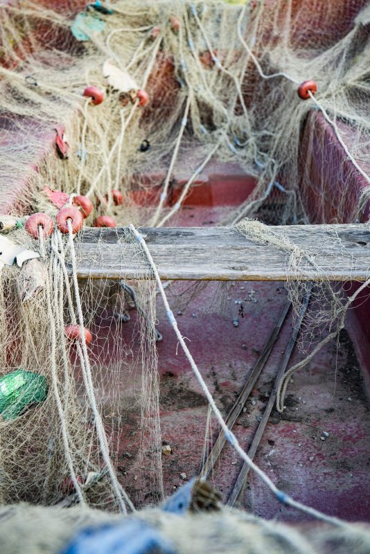 A vertical shot of an old boat covered with a fishing net